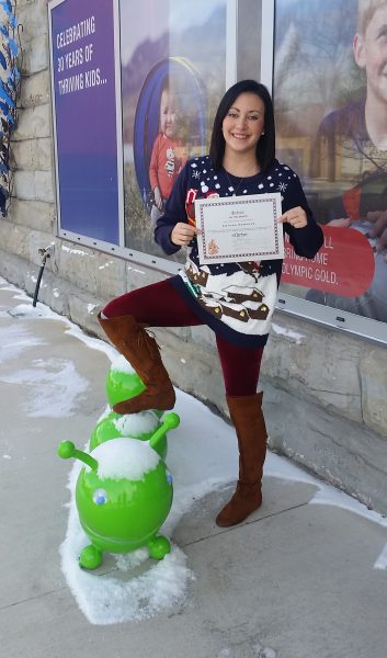 Amanda Edwards holding certificate with a foot on caterpillar sculpture
