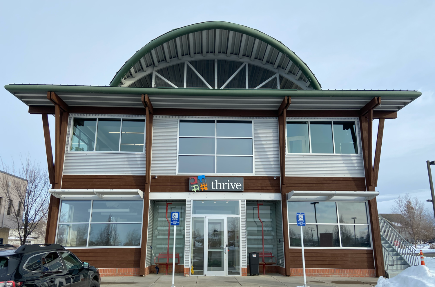 Thrive's new building front view, with the Thrive logo sign above the front door. Large metal buiding with wood accents and large panoramic windows.